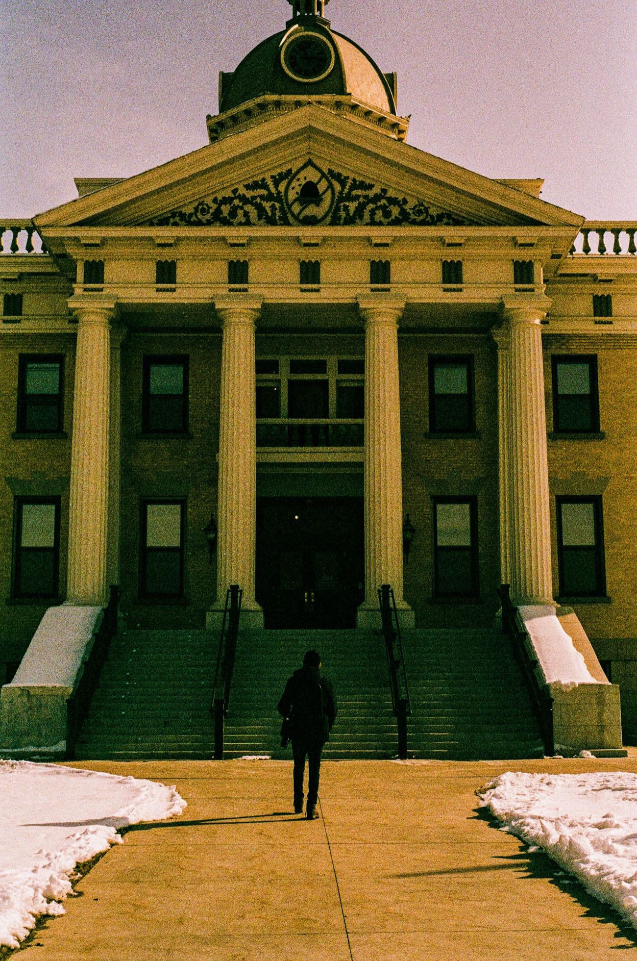 A person walking up the steps of a neoclassical county courthouse